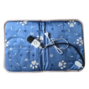 En blå rektangulär värmedyna för hundar med en bitsäker sladd, placerad i en mysig miljö för valpar och hundar.